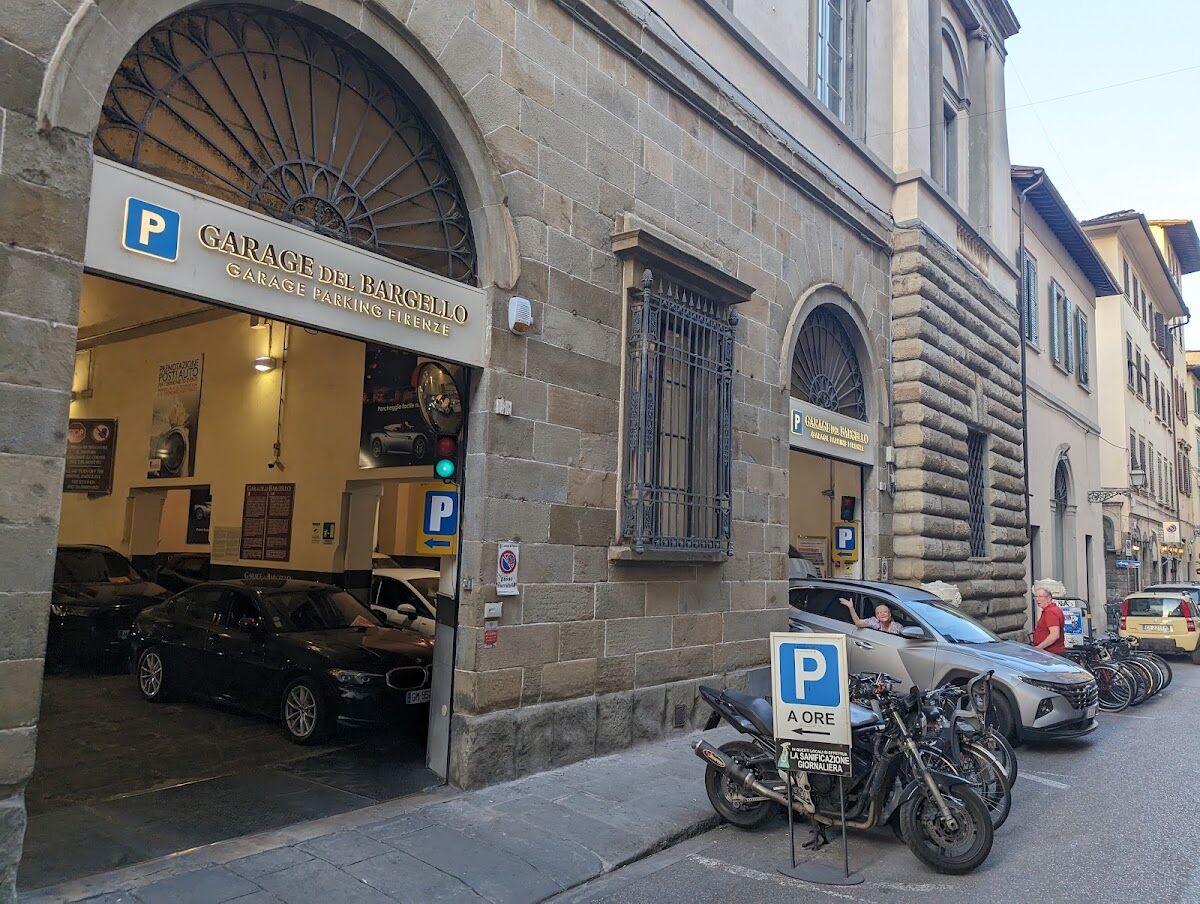 Street view of Garage del Bargello entrance with P sign, green traffic light and parked car inside, Florence