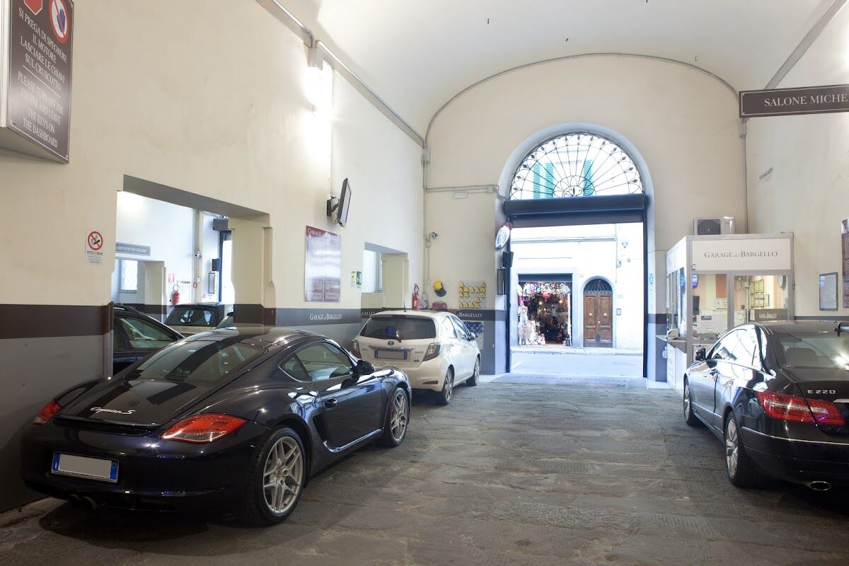 Vaulted interior of Garage del Bargello with parked cars and branded signage opening onto Via Ghibellina, Florence