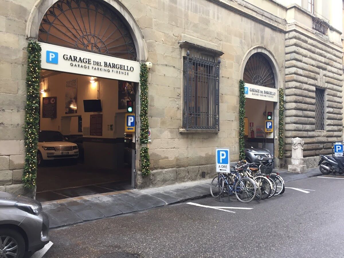Arched entrances of Garage del Bargello on Via Ghibellina with 'GARAGE DEL BARGELLO' signs and a car inside, Florence