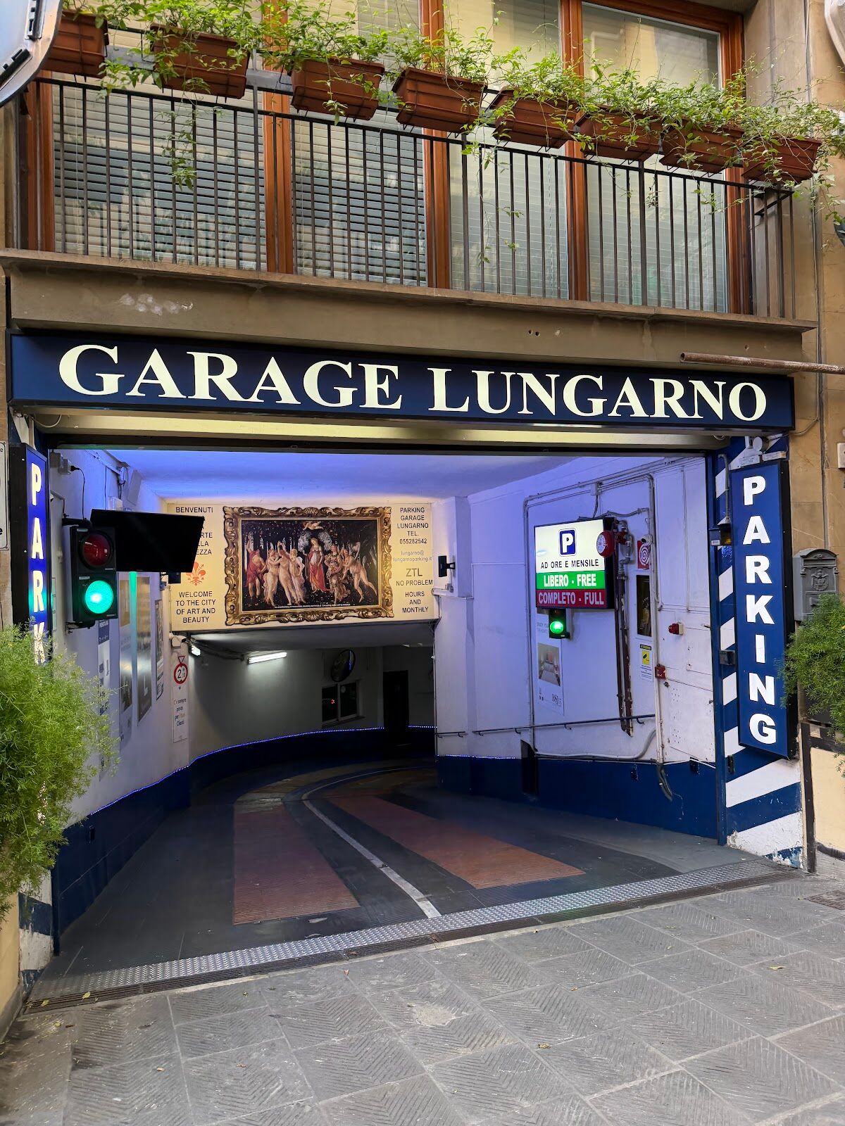 Entrance of Garage Lungarno with large 'GARAGE LUNGARNO PARKING' sign, traffic light and covered ramp, Florence