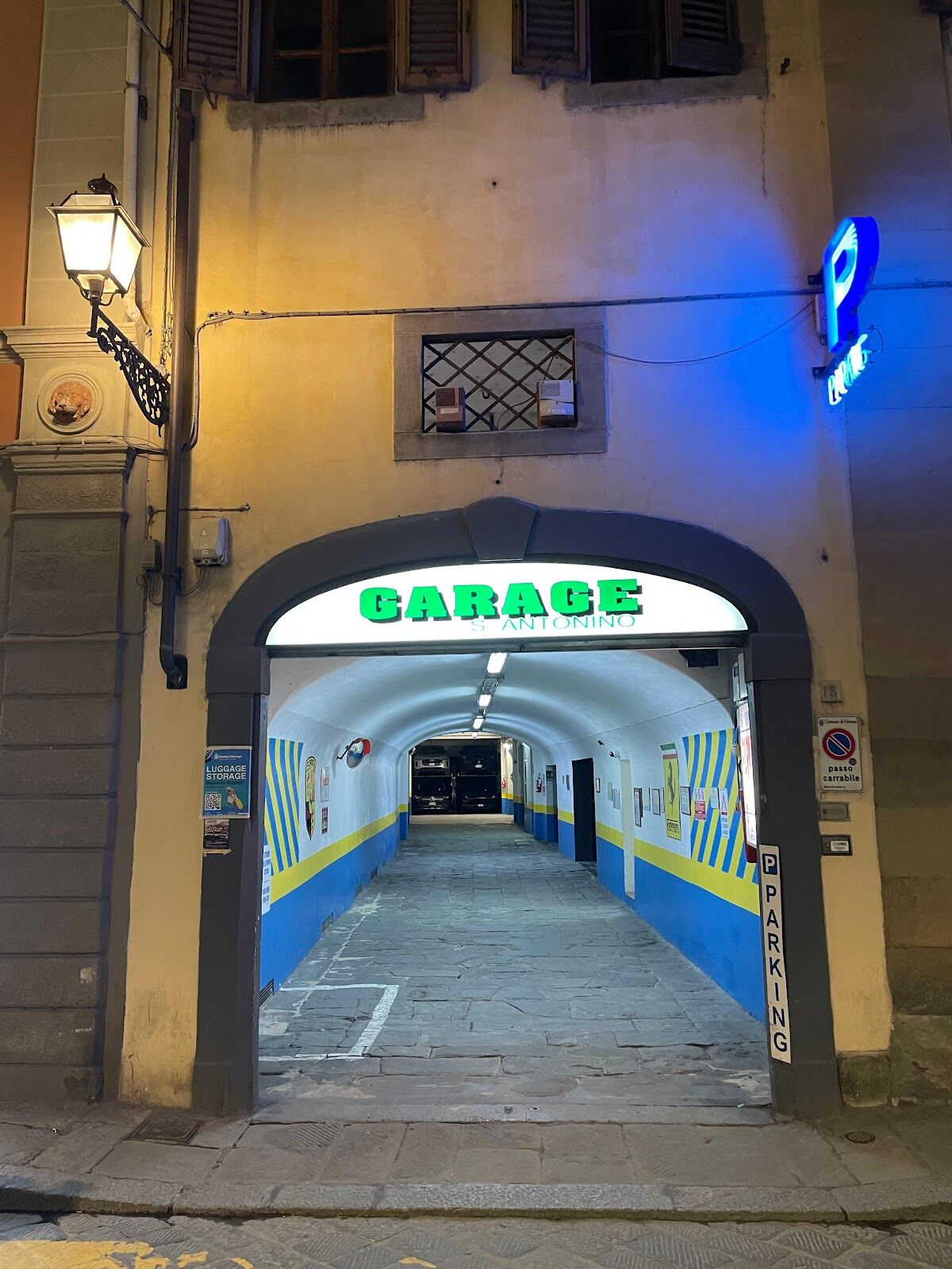 Garage S. Antonino entrance arch with lit 'GARAGE S. ANTONINO' sign and covered ramp into the parking tunnel, Florence