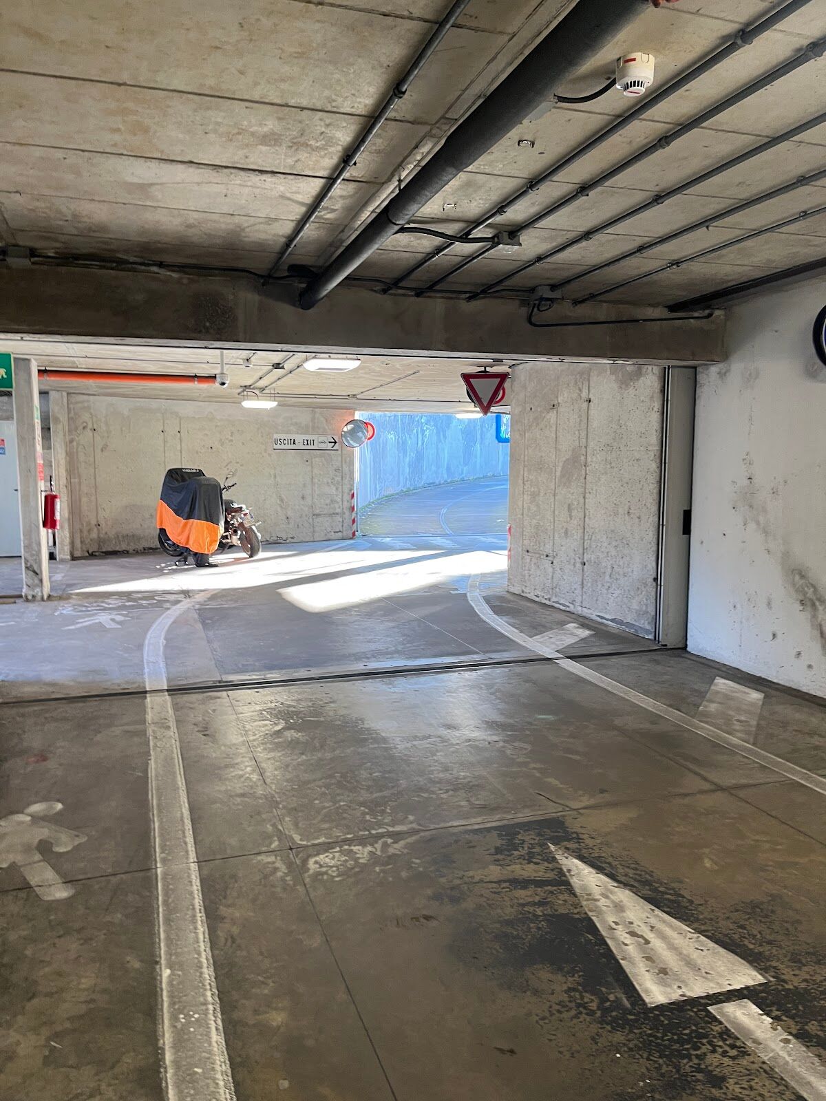 Parcheggio Parterre: covered garage exit ramp with USCITA/EXIT sign and a parked motorcycle