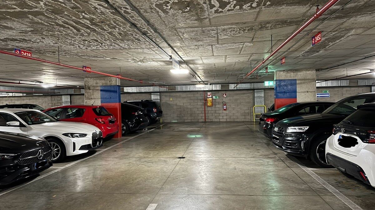 Parcheggio Parterre: covered underground garage level with parked cars and red/blue numbered columns